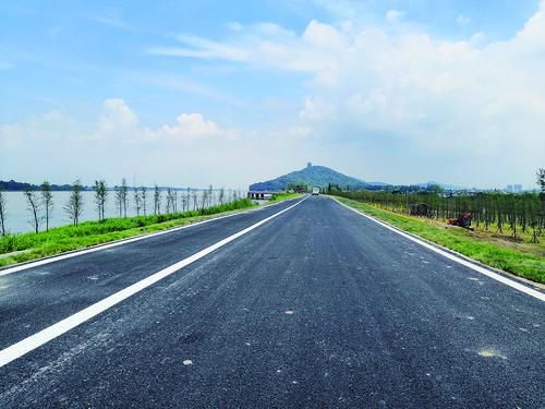 新修建的堤防堤顶沥青路 新修的沥青路平坦整洁,道路两侧绿意盎然,在